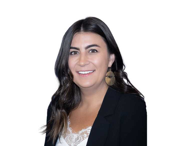 A woman wearing a black blazer and gold earrings.