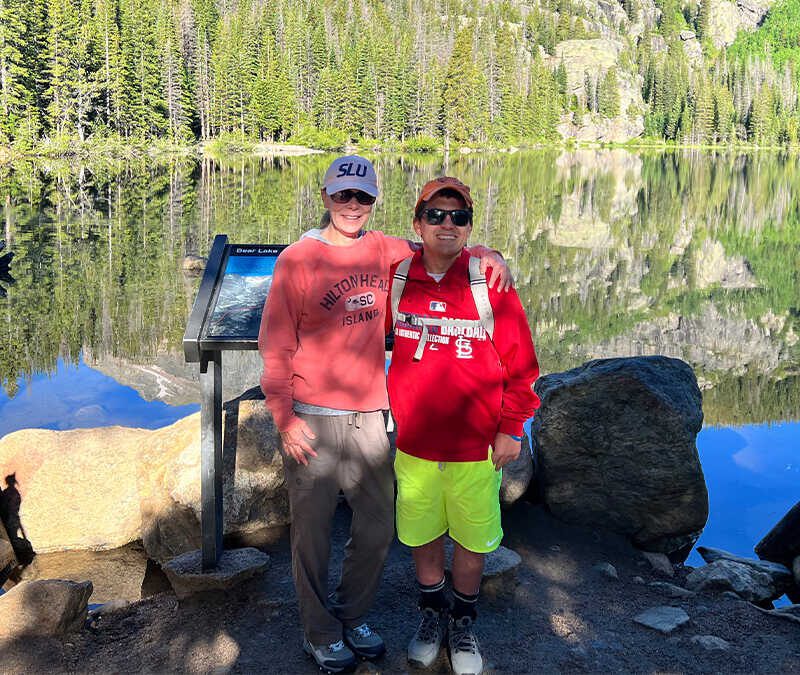 Two people standing in front of a lake.