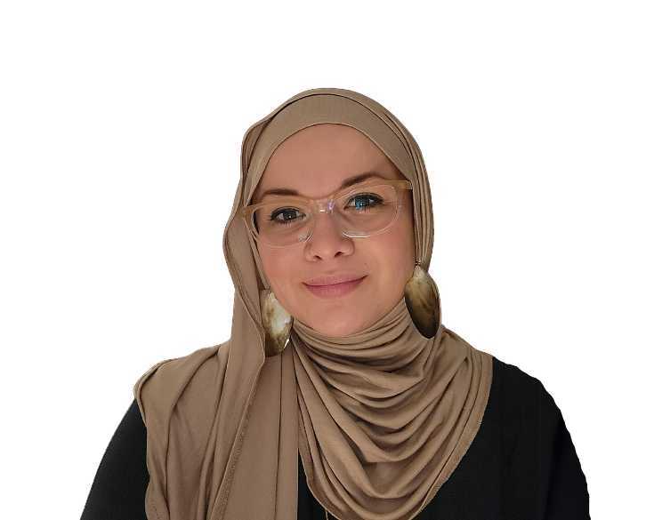 A woman wearing a beige hijab and glasses.
