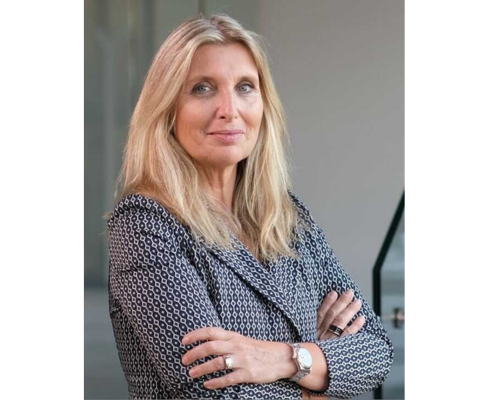 A woman in a business suit standing with her arms crossed.