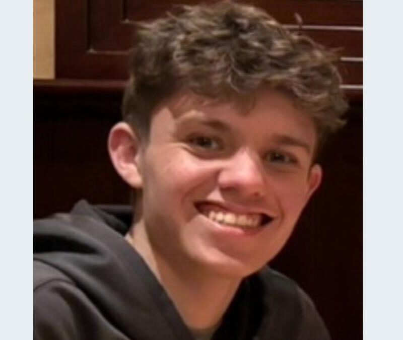 A young man smiles while sitting at a table.