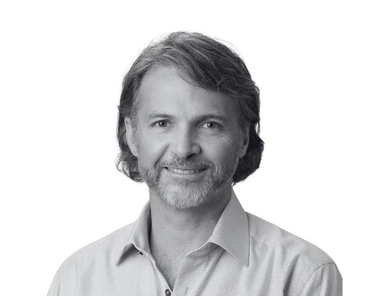 Black and white headshot of a smiling man with a beard and mustache.