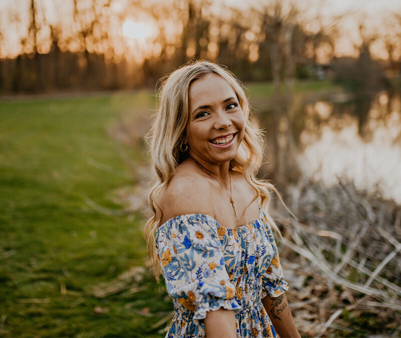 Woman smiling outdoors at sunset.