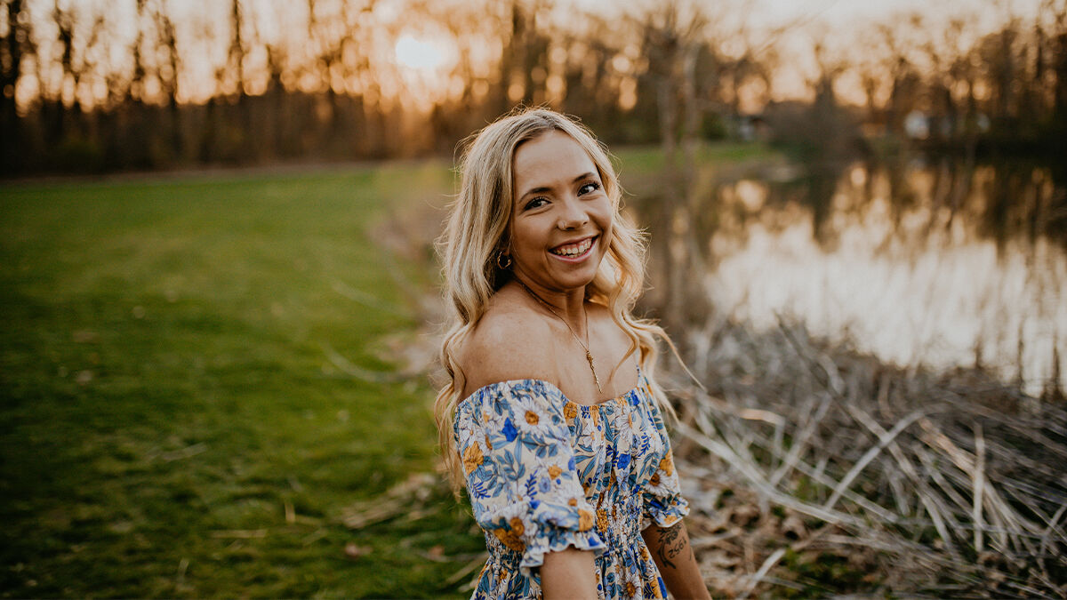 Woman smiling outdoors at sunset.