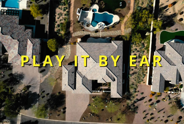 Aerial view of residential area with text overlay "play it by ear.