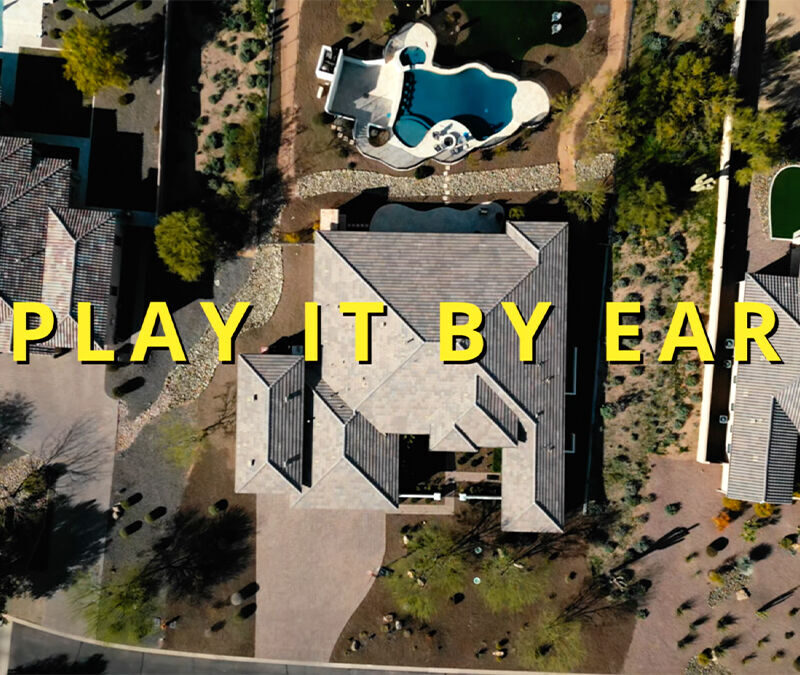 Aerial view of residential area with text overlay "play it by ear.