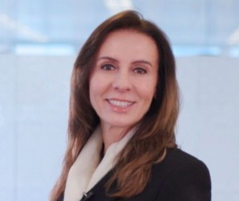 A professional woman smiling in an office environment.