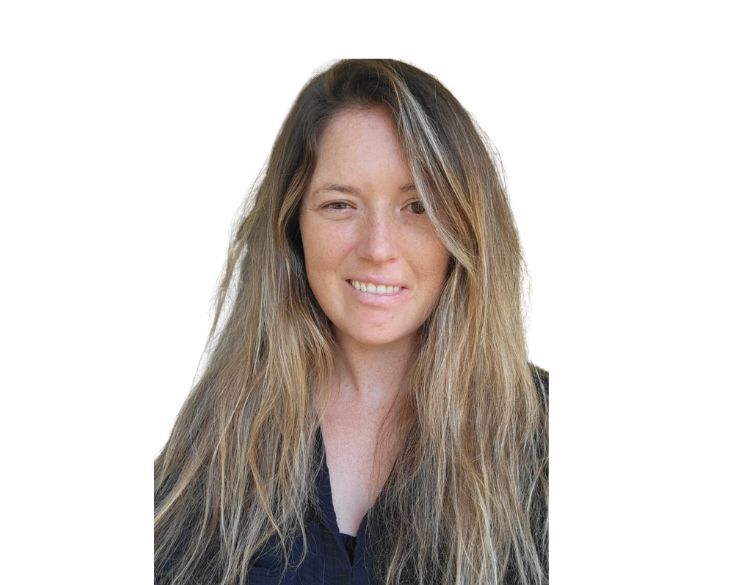 A woman with long, tousled hair smiling gently against a plain white background.