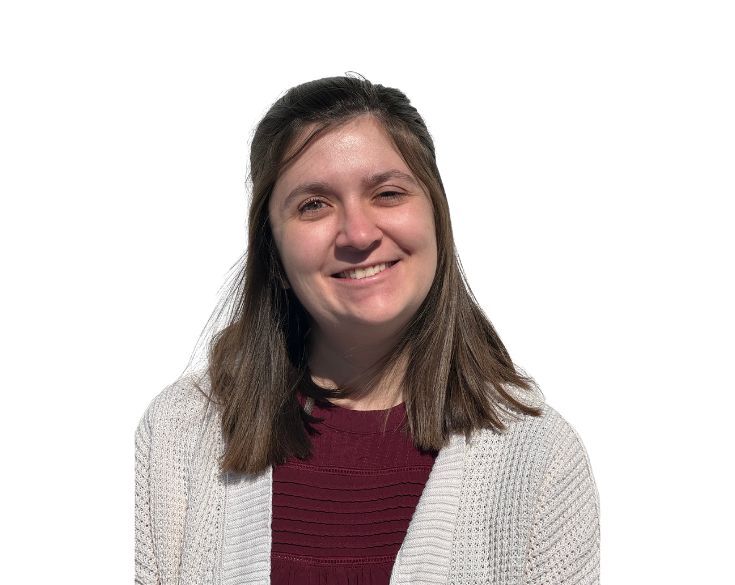 A smiling woman with medium-length hair wearing a red top and white cardigan against a plain white background.