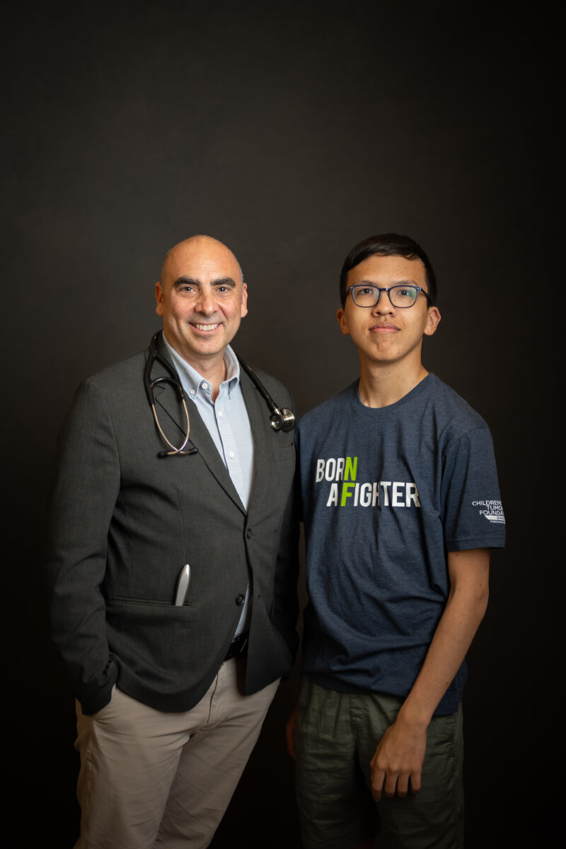 Doctor standing with a young patient wearing a 'born a fighter' t-shirt.
