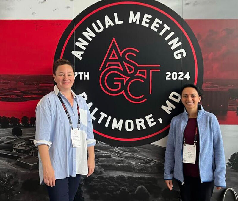 Two individuals standing in front of a banner for the "ASGCT 2024 Annual Meeting" in Baltimore, smiling at the camera.