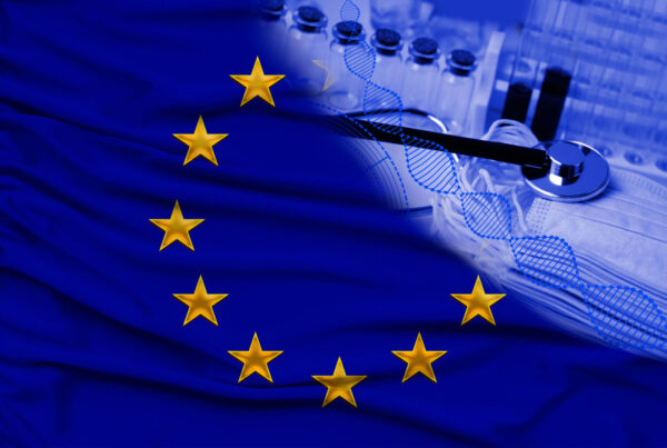EU flag with medical stethoscope, syringes, and vials on a fabric background suggesting healthcare or medical research in Europe.