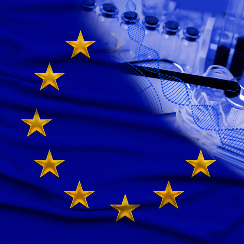 EU flag with medical stethoscope, syringes, and vials on a fabric background suggesting healthcare or medical research in Europe.