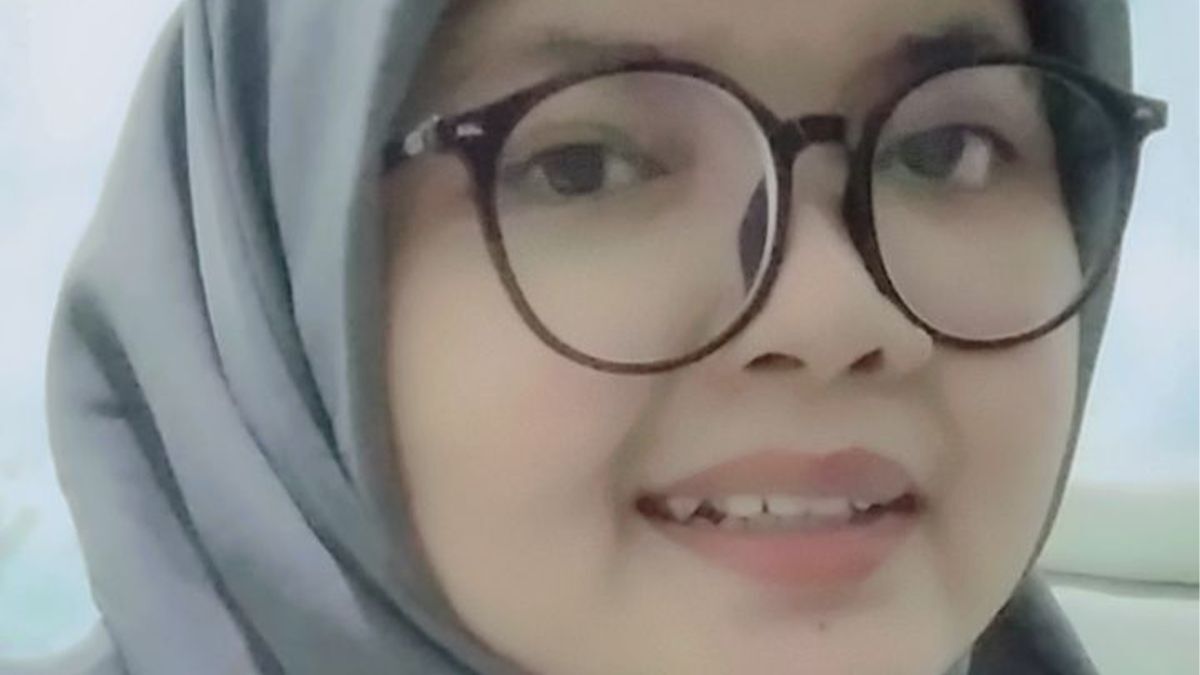 Person wearing glasses and a hijab, smiling at the camera.