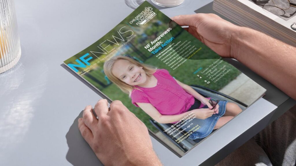 A person holds a magazine titled "NF News," featuring a smiling young girl in a pink shirt seated in a wheelchair on the cover.