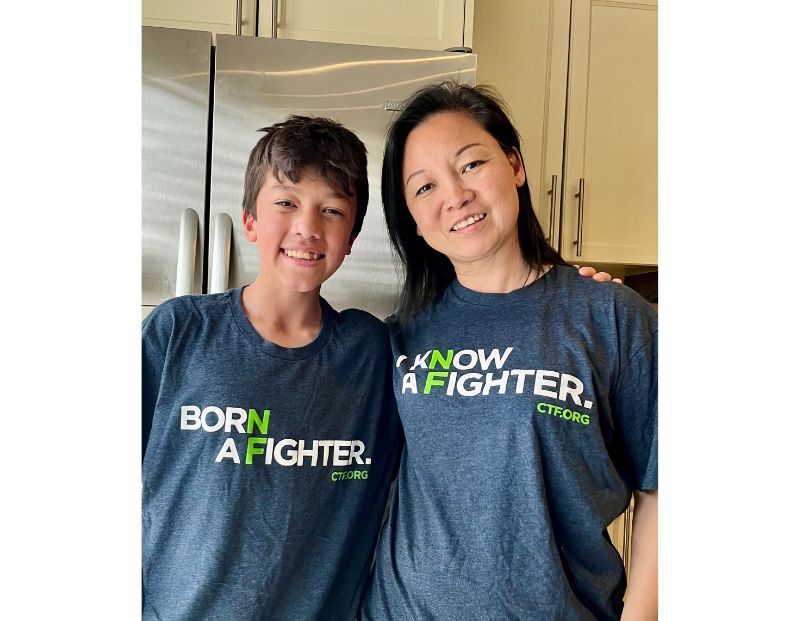 A boy and a woman stand side by side in a kitchen, both wearing navy blue shirts with green and white text promoting CTF.org.
